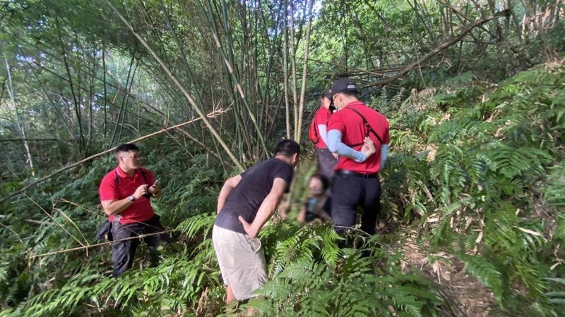 74歲王姓婦人(中)23日從新北市樹林區搭遊覽車到宜蘭一日遊,在員山鄉望龍埤不慎迷路失聯,消防人員24日清晨在一間土地公廟旁山路竹林裡尋獲王女,所幸平安無恙。(讀者提供)中央社記者王朝鈺傳真 111年7月24日