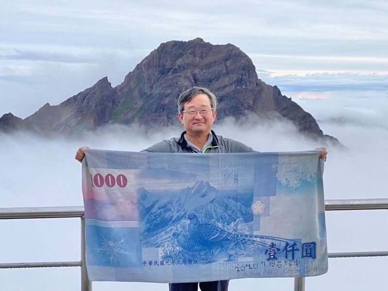 韓國駐台代表鄭炳元7月挑戰台灣最高峰玉山,並在山上跟新台幣1000元鈔票上的玉山圖案合照。(圖取自駐台北韓國代表部臉書facebook.com)