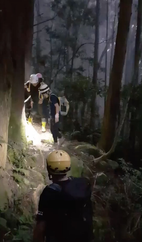 苗栗縣加里山東線1號樁附近27日發生2名女性山友滑落邊坡意外,其中一人疑因腳踝骨折無法行走,南庄消防分隊獲報出動救援,由隊員徒步輪流將傷者揹下山。(苗栗縣消防局提供)中央社記者管瑞平傳真 111年7月28日