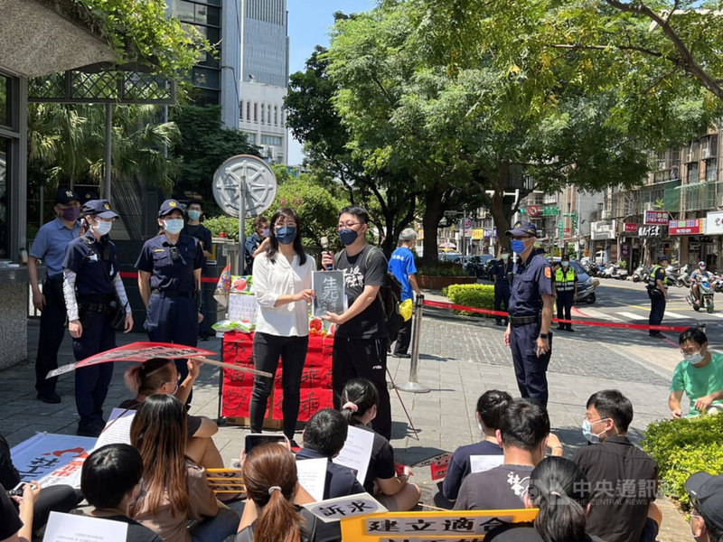 社工團體29日上午集結在衛福部大門前,以普渡法會形式表達訴求,呼籲全面檢討社會安全網政策,並送上象徵社工的「生死簿」陳情書,由衛福部社會救助及社工司科長劉雅雲(中左,白衣者)代表出面接受。中央社記者沈佩瑤攝 111年7月29日