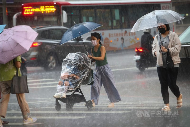 圖為台北市中山區下起大雷雨，民眾撐傘快步過馬路。（中央社檔案照片）