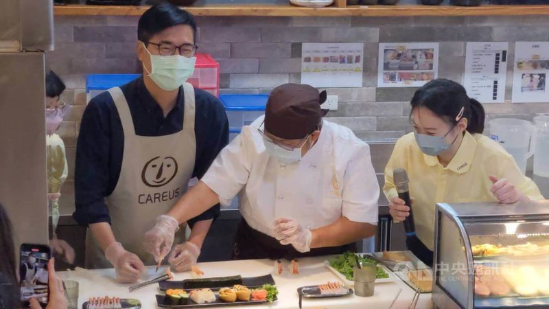 高雄市長陳其邁(左)1日前往喜憨兒創作料理庇護商店視察,並體驗製作壽司,直呼喜憨兒料理師傅「好厲害」。中央社記者曾以寧攝 111年8月1日