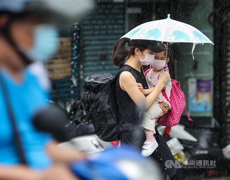 圖為北市文山區1日午後下起雷陣雨，有民眾抱著孩子撐傘遮雨。中央社記者鄭清元攝 111年8月1日