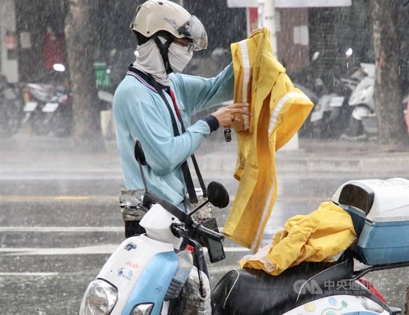 圖為1日高雄市苓雅區午後出現短暫陣雨，騎車民眾停車穿雨衣避雨。（中央社檔案照片）