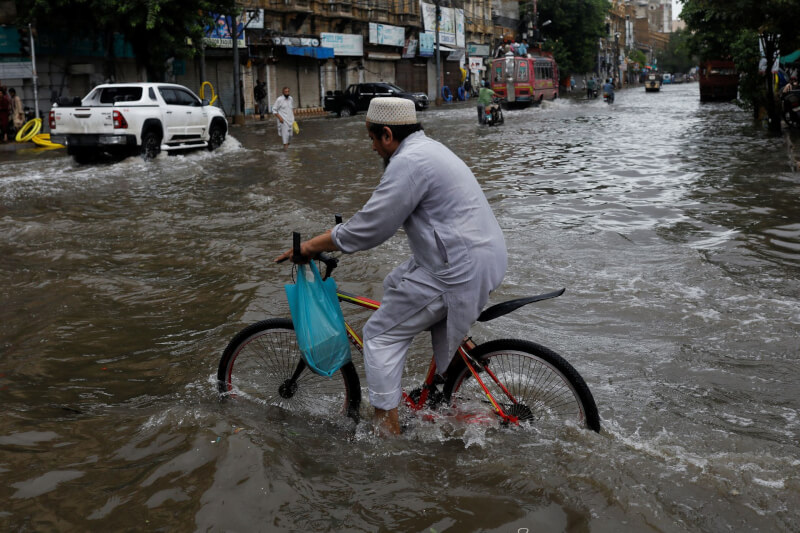 巴基斯坦異常的雨季大雨導致暴洪，在過去一個月以來至少奪走549條人命。圖為7月25日大雨過後，男子在淹水的道路上騎腳踏車。（路透社）