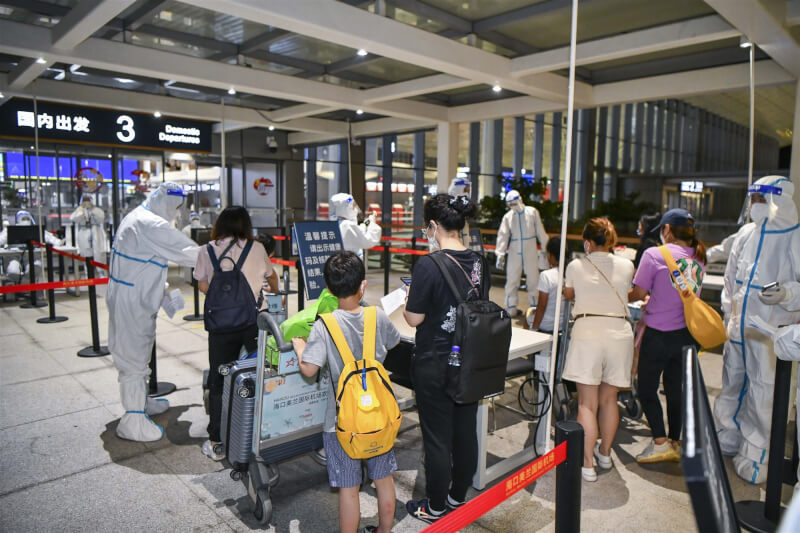 圖為12日凌晨海口美蘭國際機場工作人員檢查返程滯留遊客的購票及核酸檢測證明。（中新社）