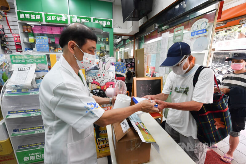 圖為台北市萬華區一間藥局，藥師將快篩試劑交給前來購買的民眾。（中央社檔案照片）