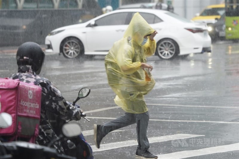 中央氣象局表示，17與18日雨勢最大。台北市中山區下起午後雷陣雨，民眾穿著雨衣快步過馬路。中央社記者徐肇昌攝 111年8月16日