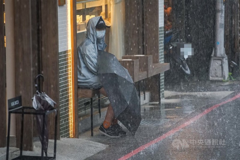 中央氣象局表示，20日午後中南部、大台北及各地山區要注意局部短暫雷陣雨。圖為台北市行人坐在商店外拿著雨傘避雨。（中央社檔案照片）