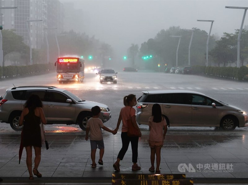 午後對流旺盛，台北市區25日下午雲層密布，隨著天色愈發昏暗，天空也降下傾盆大雨，讓人措手不及，信義區街頭有未備雨具民眾先在騎樓下躲雨。中央社記者張新偉攝 111年8月25日