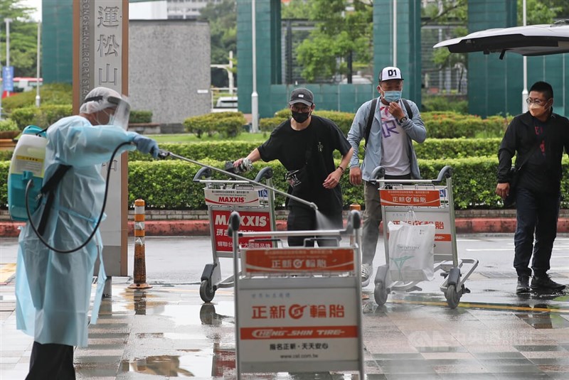 圖為6月15日入境旅客自台北松山機場搭乘親友座車離開，機場清潔人員立刻消毒走道及推車防疫。（中央社檔案照片）