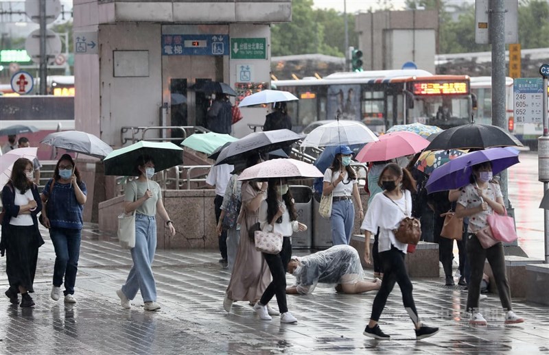 午後熱對流旺盛，台北市區25日下午下起大雨，一度天色昏暗、電閃雷鳴，至傍晚時分雨勢才開始趨緩，台北車站附近民眾撐傘活動。中央社記者張皓安攝 111年8月25日