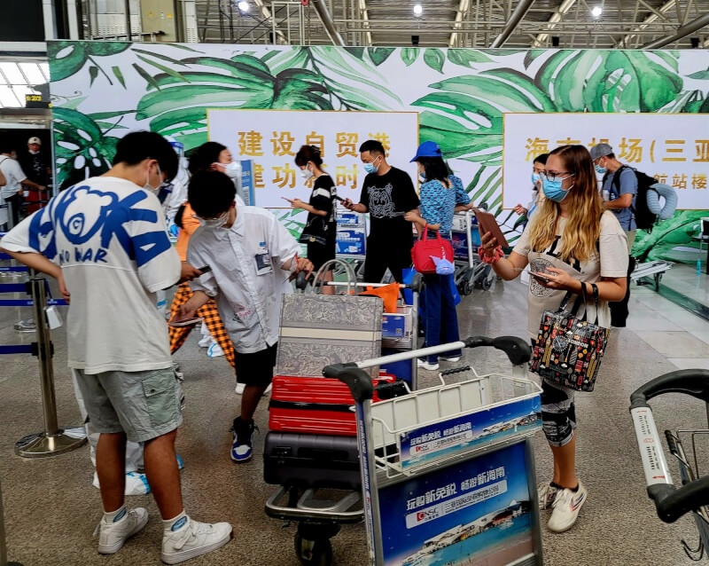 中國自31日起取消對出入境者核酸檢測訊息等申報要求，但旅客入境前仍要提供核酸檢測陰性證明才可登機。圖為15日海南三亞鳳凰國際機場旅客準備接受安檢。（中新社）