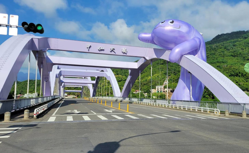 一年一度的「甲仙芋筍節」到來，超大型、將近16公尺高的可愛紫色怪獸「芋頭吼哩」攀爬在甲仙大橋上，迎接來客。（高雄市政府提供）中央社記者曾以寧傳真  111年8月27日