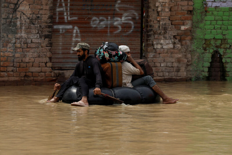 巴基斯坦各地洪患，數以萬計民眾逃離家園。圖為27日民眾帶著家當逃難。（路透社）