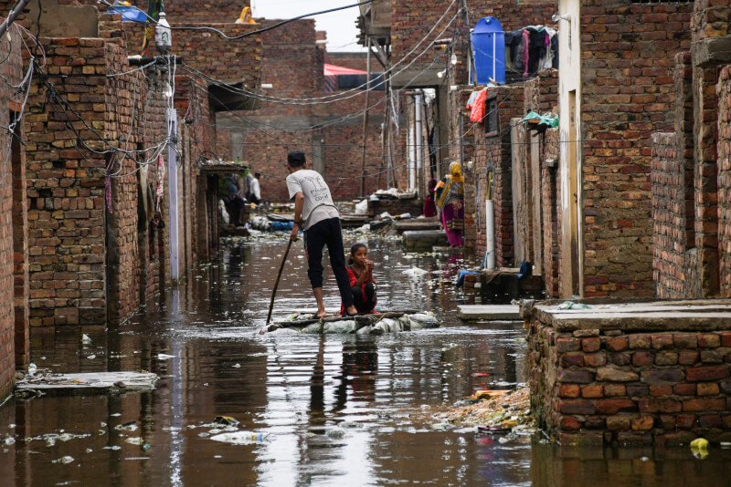圖為24日海德拉巴一對男女用臨時搭建的木筏涉水渡過被淹沒的街道。（路透社）
