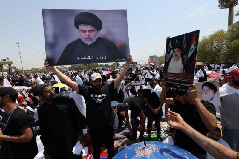圖為伊拉克首都巴格達5日可見什葉派教士薩德支持者集結，人群高舉伊拉克國旗和薩德的照片。（路透社）