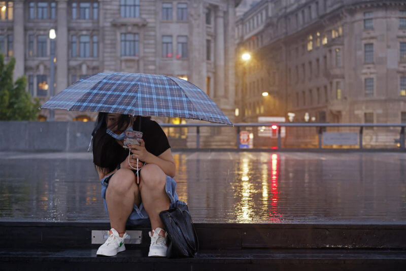 4日上海民眾冒雨在外灘濱江步道上短暫停留。（中新社）