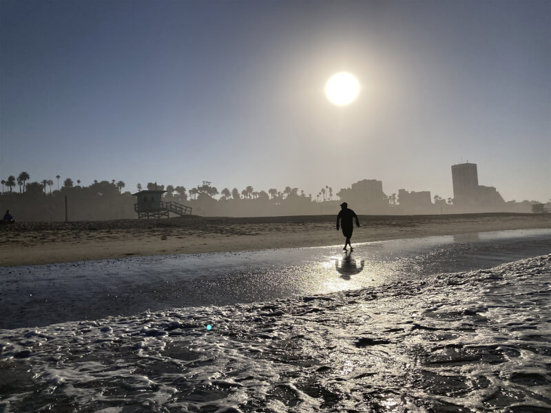 圖為加州民眾2日趁著日出在聖塔蒙尼加的海灘散步。（美聯社）