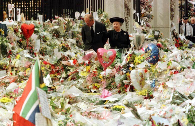 1997年英國黛安娜王妃車禍逝世,女王與菲立普親王在白金漢宮外看著大量悼念花束。(路透社)