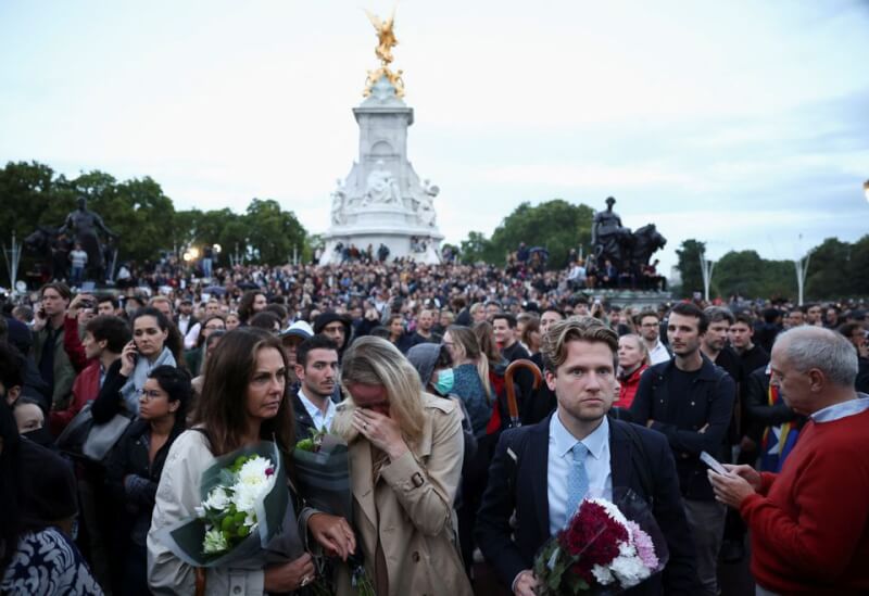 英國女王伊麗莎白二世8日辭世，民眾聚集在白金漢宮外獻花悼念，也有人不捨啜泣。（路透社）