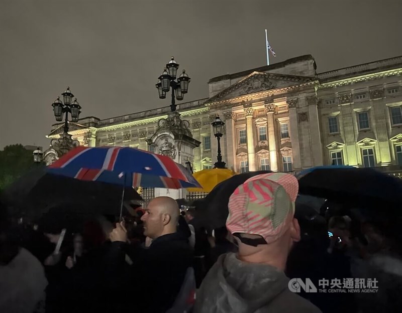 儘管有寒風陣雨，白金漢宮周邊晚間仍湧入人潮，有民眾特別持英國國旗主題雨傘前往悼念。中央社記者陳韻聿倫敦攝 111年9月9日