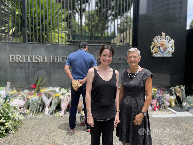 旅居新加坡的英國人麥高文（前左）與友人馬歇爾（右）10日到英國駐新加坡最高專員公署大門前獻花，向已故英國女王伊麗莎白二世致意。麥高文說，她的離開就像牆倒下了。中央社記者侯姿瑩新加坡攝  111年9月10日