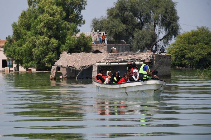 巴基斯坦水災已造成近1500人喪生。圖為11日受災民眾被救援坐在船上。（路透社）