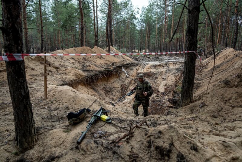 烏克蘭總統澤倫斯基15日表示，在從俄羅斯軍隊手中收復的城鎮伊久姆鎮發現一處亂葬崗。圖為烏克蘭軍人使用金屬探測器檢查一處萬人坑。（美聯社）