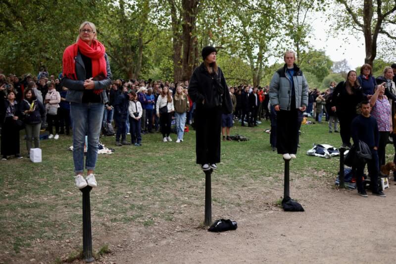 英國民眾站在柱子上觀看女王靈柩繞行經過倫敦林蔭大道。（路透社）