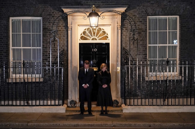 英國首相特拉斯（右） 和她的丈夫18日在倫敦唐寧街10號外為已故女王伊麗莎白二世默哀1分鐘。（美聯社）