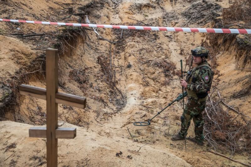 圖為烏克蘭軍人使用金屬探測器檢查伊久姆一處萬人坑。（路透社）