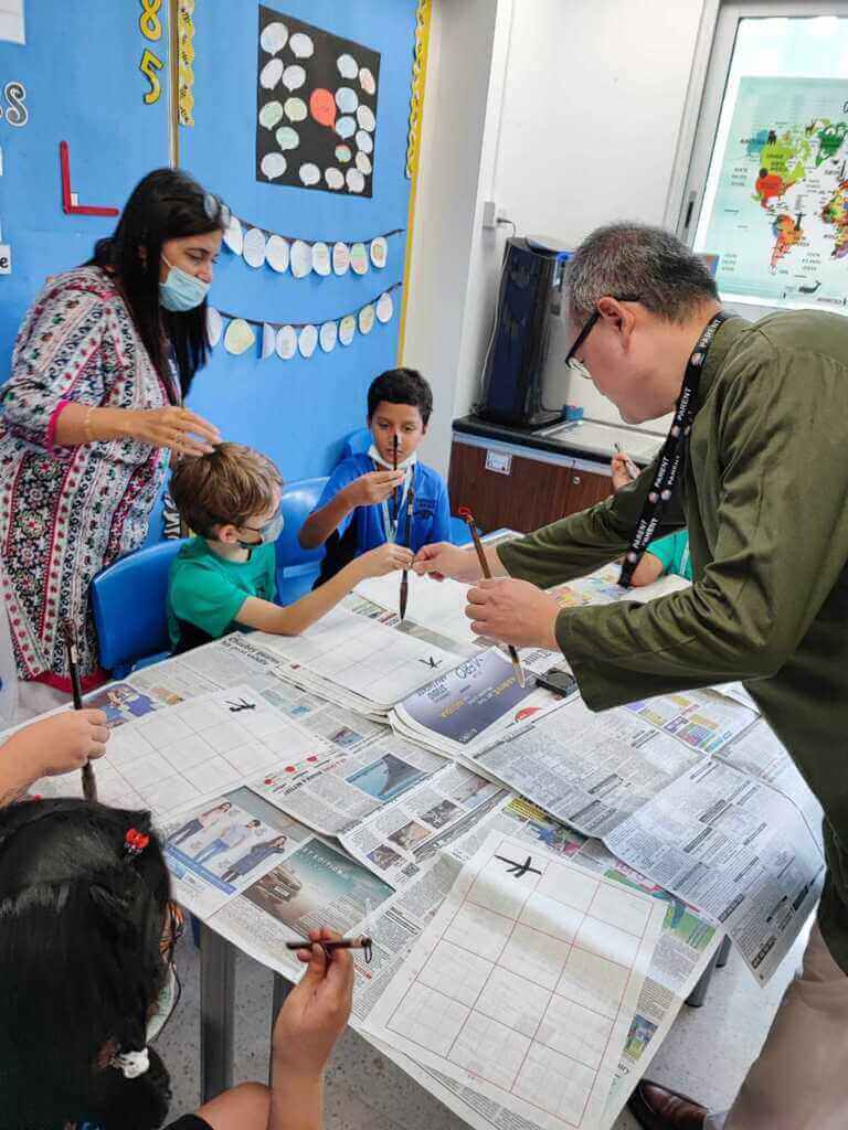 駐印度代表處教育組20日在新德里英國學校國際日活動，使用不須沾墨汁的書法水寫布教導印度學生華語與書法，讓印度學生感到很驚奇。（駐印度代表處教育組提供）中央社 111年9月22日