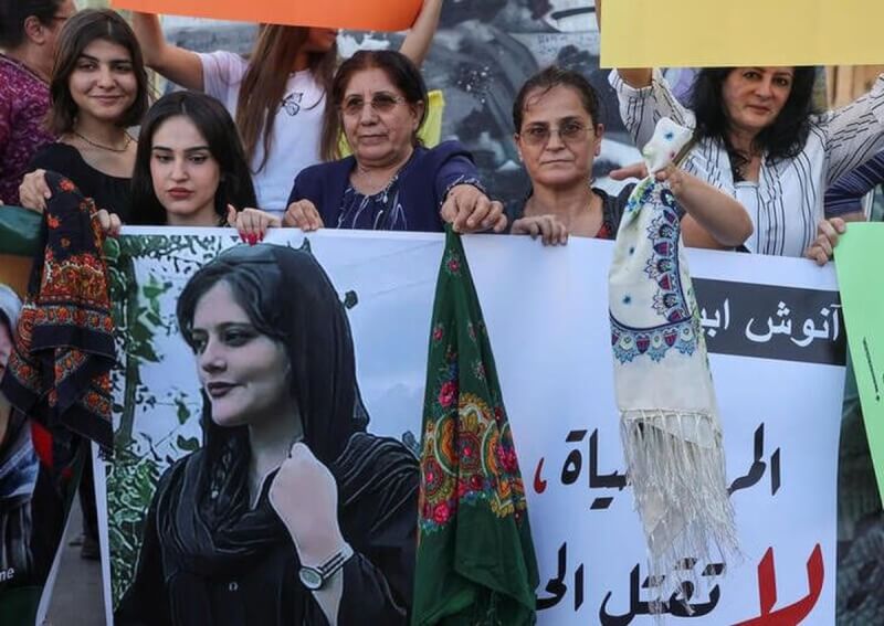 伊朗女子艾米尼遭宗教警察逮捕後去世，引發各地示威潮。圖為黎巴嫩女性21日手持艾米尼照片與頭巾走上街頭抗議。（路透社）