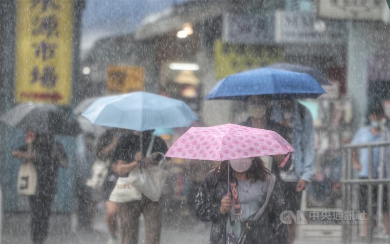 根據氣象局天氣預測，10月1日至3日，西北太平洋及南海上持續有颱風生成發展的機率。圖為民眾在公館商圈撐傘避雨。（中央社檔案照片）