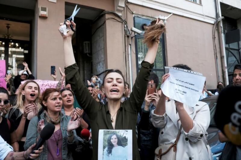 伊朗女子艾米尼遭「宗教警察」羈押後死亡引發民眾抗議，伊朗約80個城市和其他市區中心都出現抗議活動。圖為居住在土耳其的伊朗婦女21日在抗議時激動剪下頭髮。（路透社）