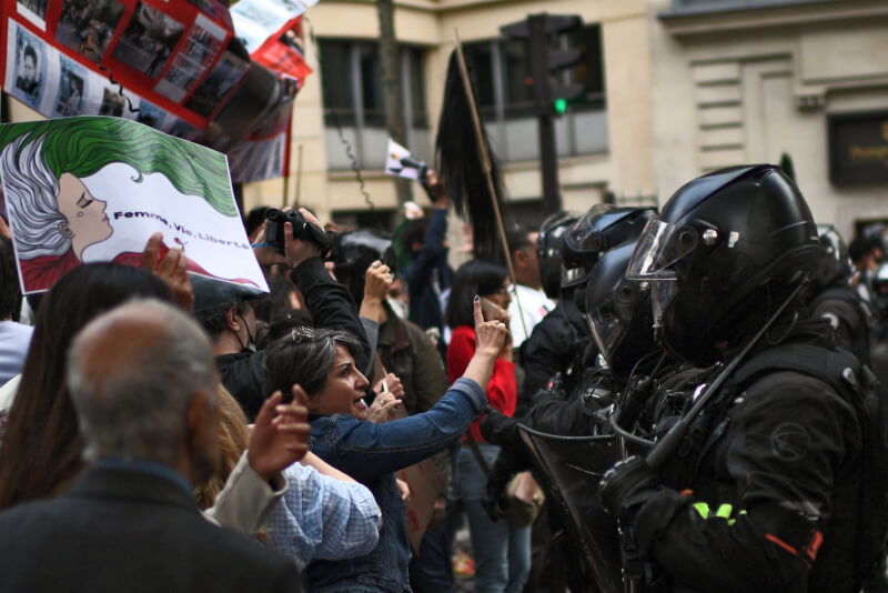 法國巴黎民眾25日為伊朗女子艾米尼之死上街抗議，與防暴警察對峙。（法新社）