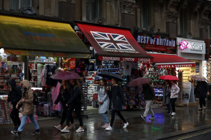 圖為民眾27日撐傘在倫敦市中心逛街。（路透社）