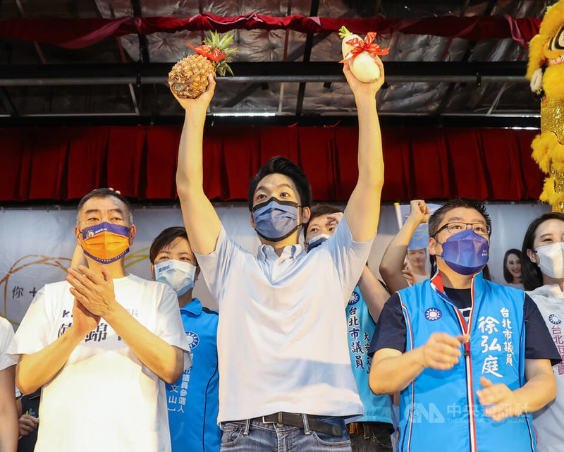 國民黨台北市長參選人蔣萬安（前中）2日出席文山區後援會成立大會，他上台時高舉主辦單位致贈的鳳梨、菜頭，為選情祈求好彩頭。中央社記者鄭清元攝　111年10月2日