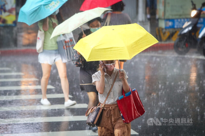 氣象專家吳德榮表示，5日東北季風抵達，北台轉有雨，高溫降至約28度。圖為台北市中山區民眾撐傘擋雨。（中央社檔案照片）