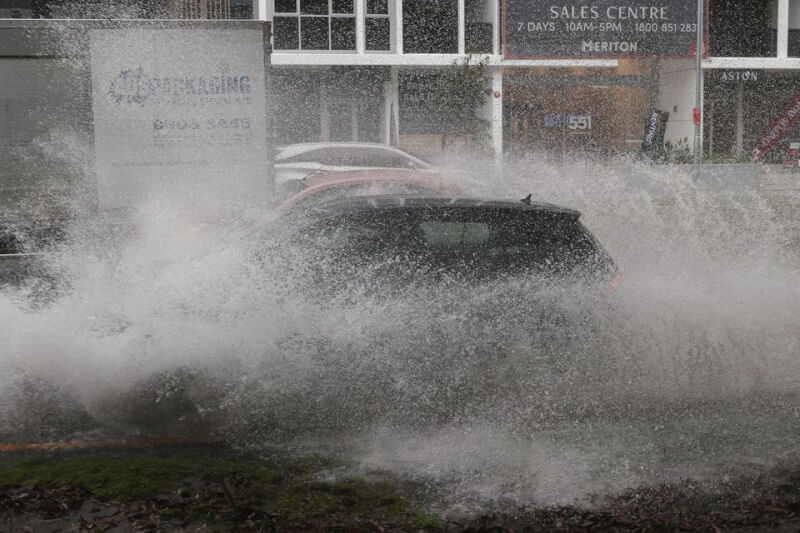 澳洲雪梨近期大雨不斷，車輛6日行經道路積水時濺起水花。（路透社）