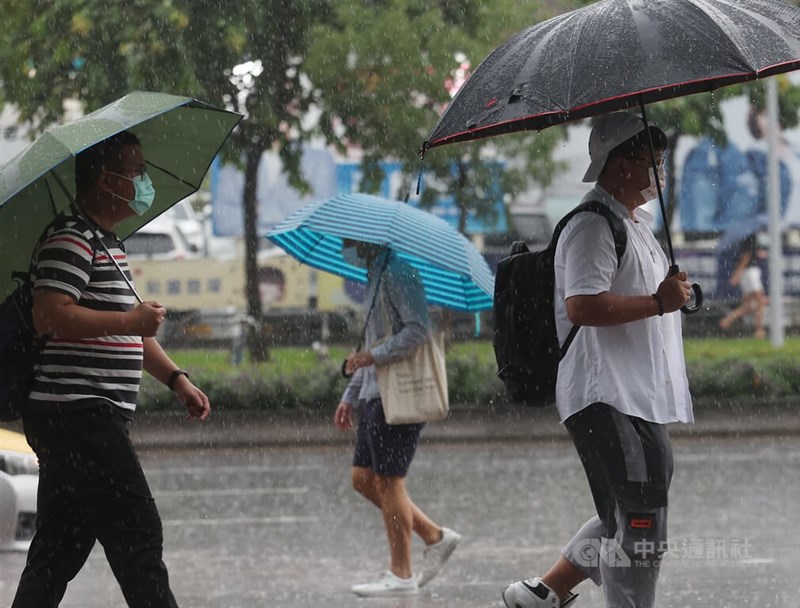 圖為台北市信義區降雨，民眾撐傘遮擋雨勢。（中央社檔案照片）