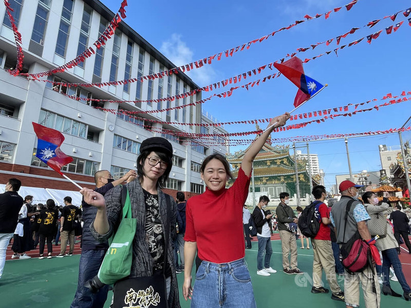日本橫濱僑界舉辦雙十國慶活動，橫濱中華學校及周邊的中華街張燈結彩。旅居橫濱的台僑吳小姐（右）與日籍男性友人前來，她看到國旗喊「很激動、很感動。」中央社記者楊明珠橫濱攝  111年10月10日