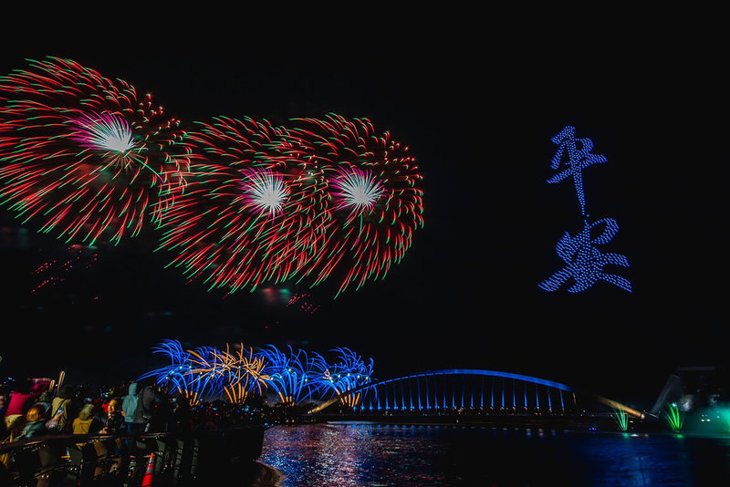 2022國慶焰火在嘉義，10日晚間在故宮南院盛大舉行，絢麗煙花結合水舞光雕、無人機秀及台北愛樂管弦樂團現場演出，時間長達45分鐘。圖為焰火在夜空綻放同時，無人機也於一旁排列出平安2字。（嘉義縣政府提供）中央社記者蔡智明傳真  111年10月10日