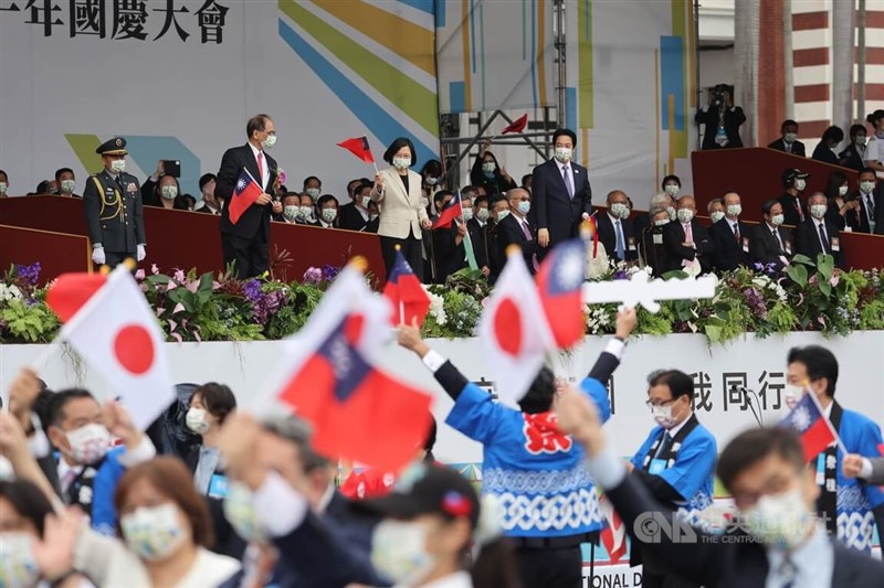 「中華民國中樞暨各界慶祝111年國慶大會」10日在總統府前廣場登場，日本國會跨黨派友台團體日華議員懇談會、立法院台日交流聯誼會進場通過台前，總統蔡英文（台上前中）、副總統賴清德（台上前右）與國慶籌備委員會主委、立法院長游錫堃（台上前左）揮舞國旗致意。中央社記者王飛華攝 111年10月10日