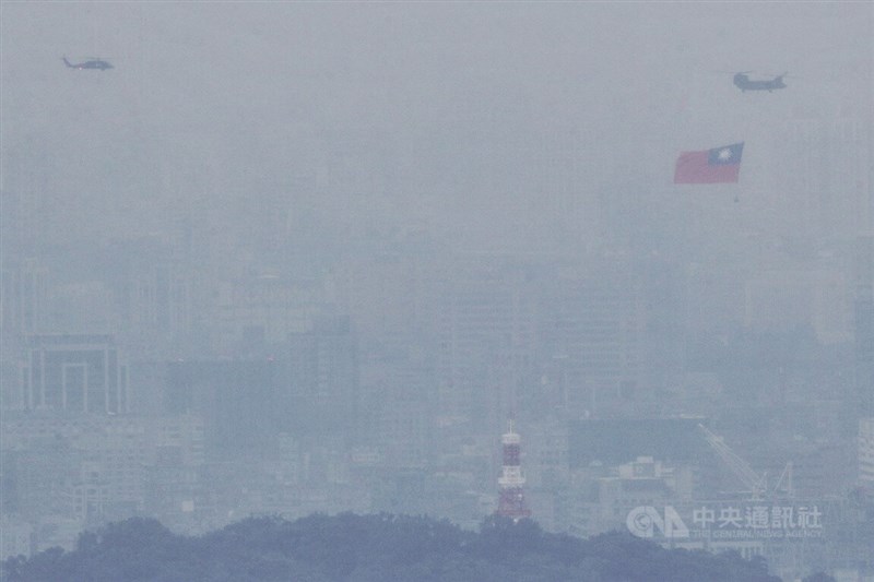 中華民國中樞暨各界慶祝111年國慶大會10日登場，國軍CH-47SD契努克運輸直升機吊掛巨幅國旗，與UH-60M黑鷹直升機在雲霧中往總統府前上空飛行。中央社記者裴禛攝 111年10月10日