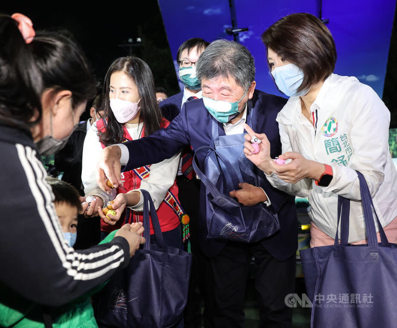 民進黨台北市長參選人陳時中(右2)10日晚間到木柵國中出席紙風車劇團「巫頂環遊世界」演出活動,跟同黨市議員簡舒培(右)等人一起發玩具給小朋友們。中央社記者鄭清元攝 111年10月10日