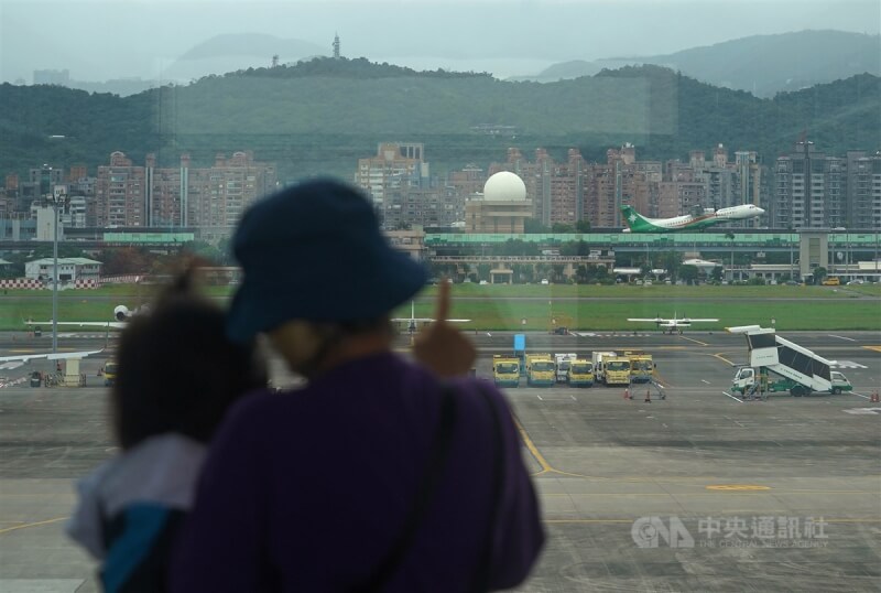 指揮中心宣布，13日起全球COVID-19旅遊疫情建議降為第二級（警示：Alert）。圖為家長帶孩子在台北松山機場觀看飛機起降。（中央社檔案照片）