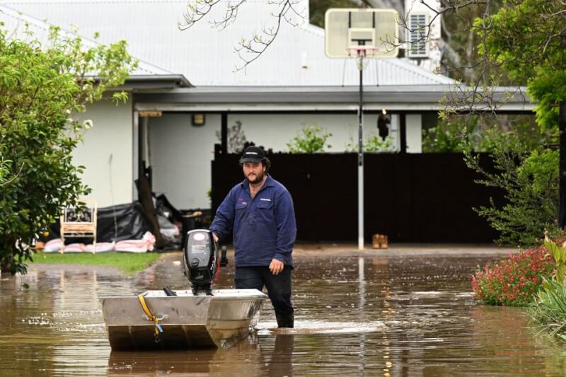 澳洲多地受到極端氣候衝擊降下暴雨，引發洪水災情。圖為居民推著船在積水中撤離。（AAP Image/James Ross via 路透社）
