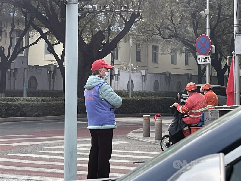 中共20大16日開幕，北京街頭除了制服員警，還有一些社區志願者及各式各樣的協警及保安。圖為北京國家體育總局旁一處路口，1名老年志願員站在斑馬線與快慢車道交界處，緊盯著路口四周動靜。中央社記者邱國強北京攝 111年10月15日